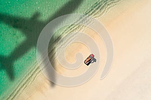 Concept of airplane travel to exotic destination with shadow of commercial airplane flying above beautiful tropical beach. Beach