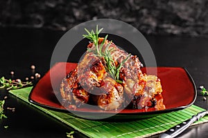 Concept of American cuisine. Glazed pork ribs barbecue with rosemary on a red plate. Beautiful serving in the restaurant.