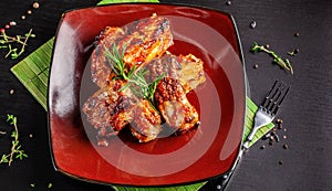 Concept of American cuisine. Glazed pork ribs barbecue with rosemary on a red plate. Beautiful serving in the restaurant.