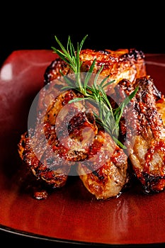 Concept of American cuisine. Glazed pork ribs barbecue with rosemary on a red plate. Beautiful serving in the restaurant.