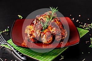 Concept of American cuisine. Glazed pork ribs barbecue with rosemary on a red plate. Beautiful serving in the restaurant.