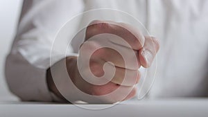 The concept of anger. The man beats his fist on the table showing aggression at white background