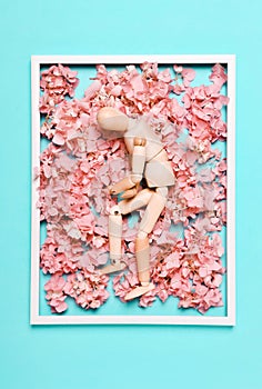 Concept,  art, creative. Wooden mannequin on a background of flowers. Depression concept, sadness, problem