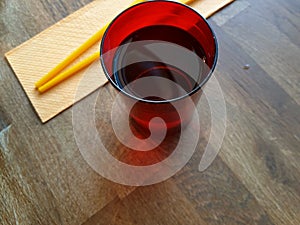 Concept of Asian restaurant. Table top view with colorful chopsticks on a napkin and bright red water mug. Vietnamese dining.