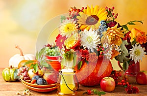 Concept of autumn festive decoration for Thanksgiving day. Autumn bouquet of flowers and berries in a pumpkin on a table,