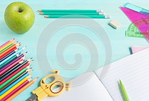 Concept back to school.School accessories, colored pencils, pen with empty notebook on blue wooden background