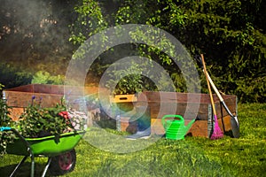 Wheelbarrow with Gardening tools in the garden. watering in the garden. rainbow formation