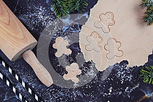 Concept for baking Christmas cookies with rolled out cookie dough, cookies in the shape of happy gingerbread men, rolling pin