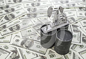 Concept barrel and oil drilling pump on background of US dollar banknote.