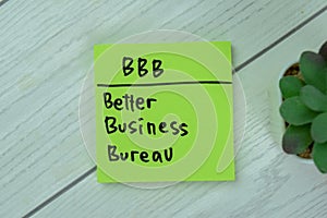 Concept of BBB - Better Business Bureau write on sticky notes isolated on Wooden Table photo
