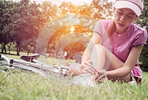 Concept bike accident, Woman with pain in knee joints after biking on bicycle in park. Ankle hurts after bike fall