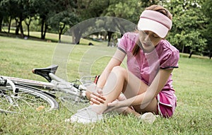 Concept bike accident, Woman with pain in knee joints after biking on bicycle in park. Ankle hurts after bike fall