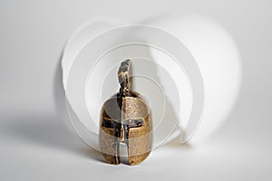 The concept of the birth of a warrior. Gladiator`s bronze helmet next to a broken egg shell on white background