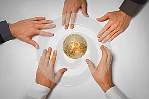 Concept of a bitcoin hype with five hands reaching for a bitcoin coin