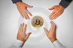 Concept of a bitcoin hype with four hands reaching for a bitcoin coin