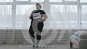 Concept body positivity - a chubby woman holds a sign with the inscription PERFECT