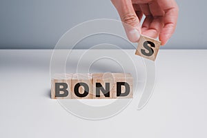Concept of bonds. Businessman puts wooden blocks with the word Bonds. Equivalent loan. Unsecured and secured bonds. Bonds