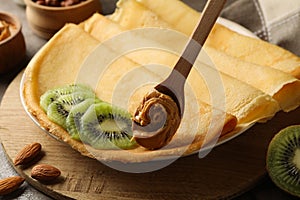 Concept of breakfast with crepes with kiwi and spoon with peanut butter