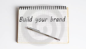 Concept BUILD YOUR BRAND message on the notebook on white background