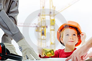 Concept, builders are discussing with child over drawing. Helmet protective equipment construction city site, cranes