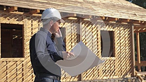 Concept building constructing architect slow motion video. man builder in a helmet stands at a construction holding a