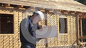 Concept building constructing architect slow motion video. man builder in a helmet stands at a construction holding a