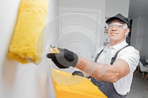 Concept building, painter in gloves and uniform holding painting roller repair apartment home