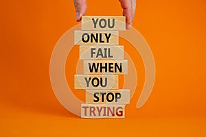 Concept of building success foundation. Men hand put wooden blocks on the stack of wooden blocks. Text `you only fail when you