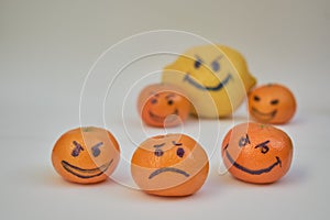 Concept of bullying, discrimination. Group of laughing emoticon faces and one alone look sad and depressed. Lemmons and mandarines