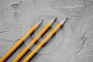 Concept of business, Back to school, three sharpened pencils on a background of gray plaster texture, space for text