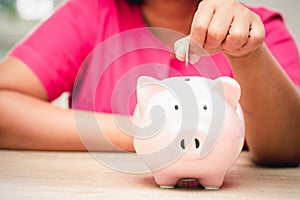 Concept business woman hand putting money coin into piggy bank saving money for future plan and retirement fund