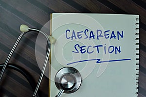 Concept of Caesarean Section write on a book with stethoscope isolated on Wooden Table