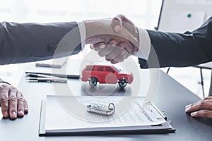 Concept of Car insurance or rental, salesman shaking hand with buyer aafter sign sell contract or sell agreement