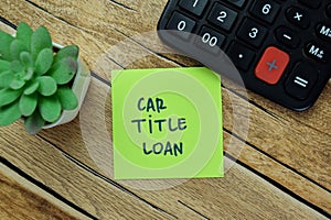 Concept of Car Title Loan write on sticky notes with calculator isolated on Wooden Table