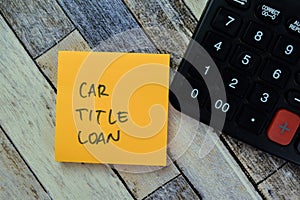 Concept of Car Title Loan write on sticky notes with calculator isolated on Wooden Table