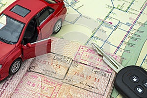 The concept of car travel: the passport with the border stamps. City map and car keys. Red car model.