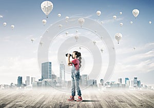 Concept of careless happy childhood with girl looking in binoculars