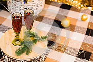 The concept of celebrating Christmas at home. Glasses with red wine on table under Christmas tree decorated with garland