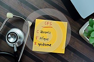 Concept of CFS - Chronic Fatigue Syndrome write on sticky notes with stethoscope isolated on Wooden Table