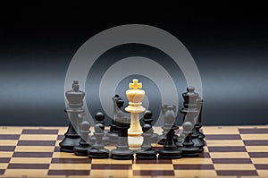 Concept of a chief person surrounded by enemies, threatened, with no way out. Made with chess figures on the chessboard