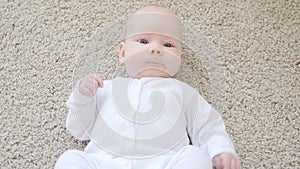 Concept of children and parenthood. Cute Happy Baby is Lying on Carpet