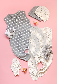 The concept of children`s clothing. set of white and gray children`s clothes on a light pink background. Sliders, toys, mittens