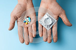 Concept choice of contraception, pill or condom. The man in his hand are birth control pills and in the second hand condom