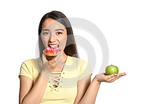 Concept of choice. Woman eating doughnut and holding apple on white background