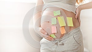Concept of choosing baby name. cropped shot of pregnant woman with question marks on paper stickers on tummy