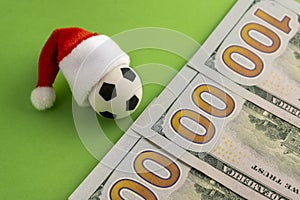 The concept of Christmas football victory or defeat. New Year sports betting or gift. Toy soccer ball in a red Santa Claus hat