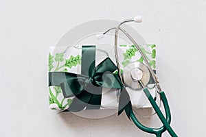 Concept of Christmas Medicine. Medical stethoscope and gift box on light background. Flat lay