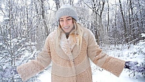 The concept of Christmas and winter holidays. Happy woman throws snow in the winter forest