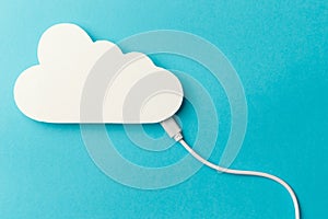 The concept of cloud technologies, cloud storage. A white cable is connected to a cloud on a blue background. Top view