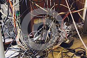 Concept of clutter in office. Unwound and tangled electrical wires under the table. photo